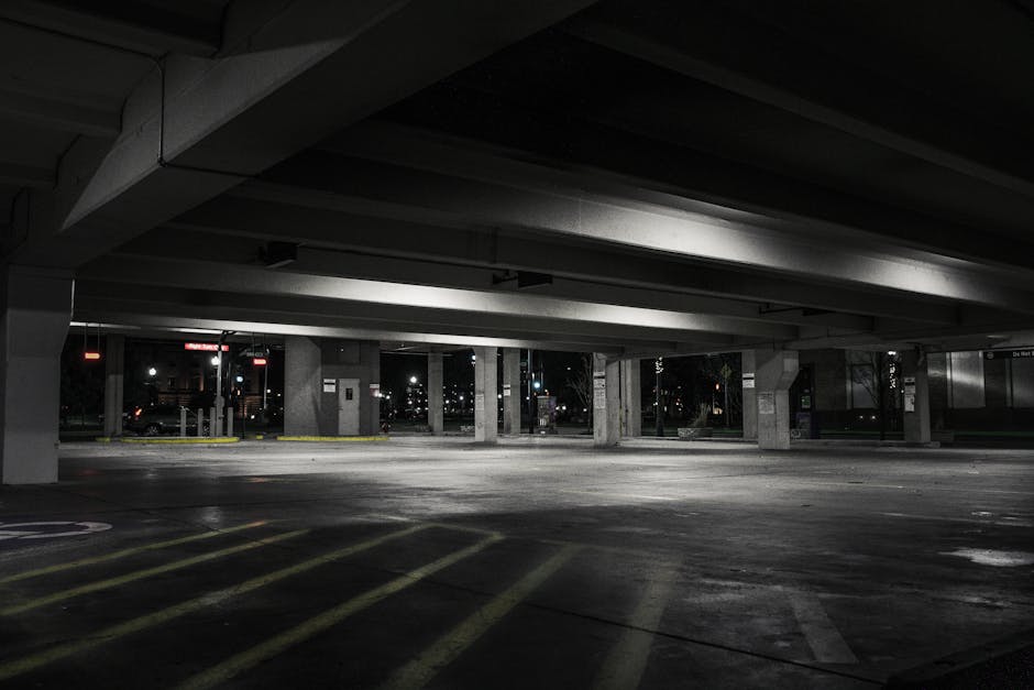 An empty urban parking garage at night with dramatic lighting creating a moody atmosphere.